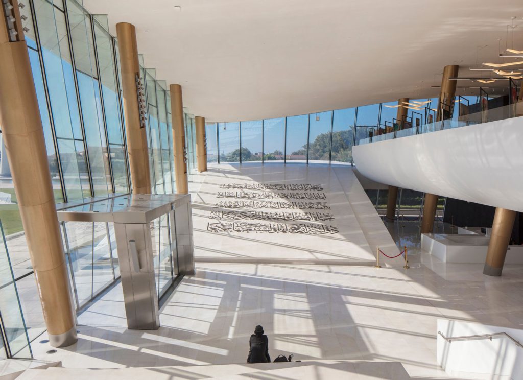 Marble covered atrium at Etihad Museum, with sloped floor of Declaration of Independence in Arabic.