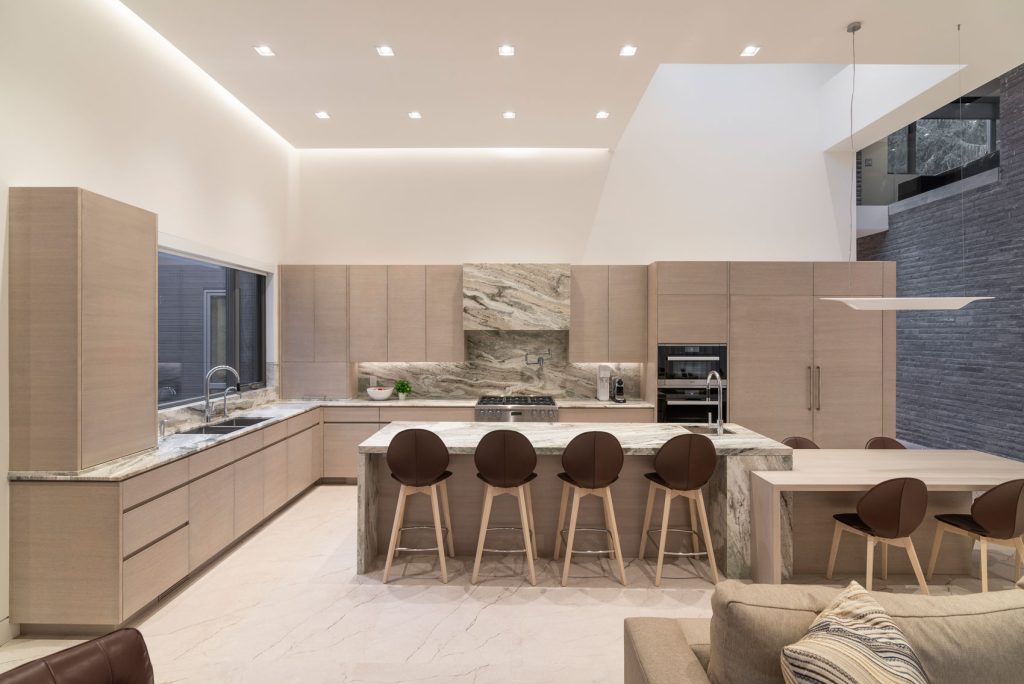 A vast kitchen with pale panelling is the backdrop for a long island with two heights and bar sink.