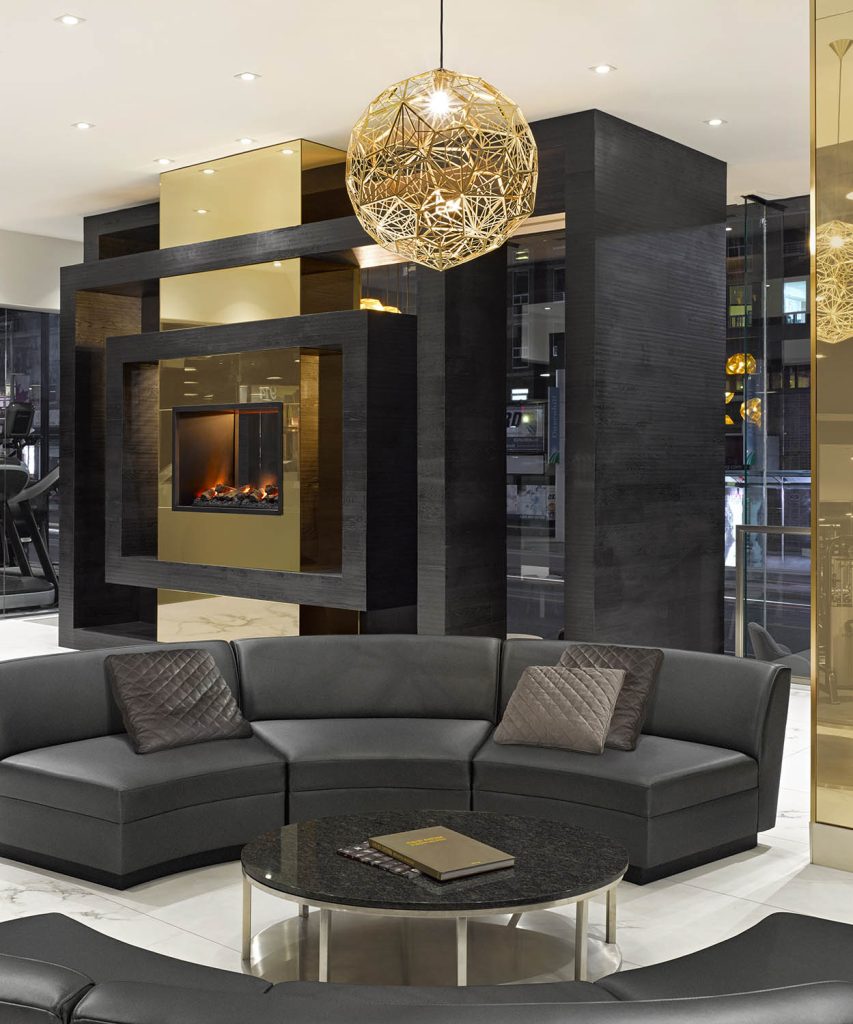 Waiting and lounge area with circular sectionals for seating and a beautiful accent light fixture above. The fire place is in the background.