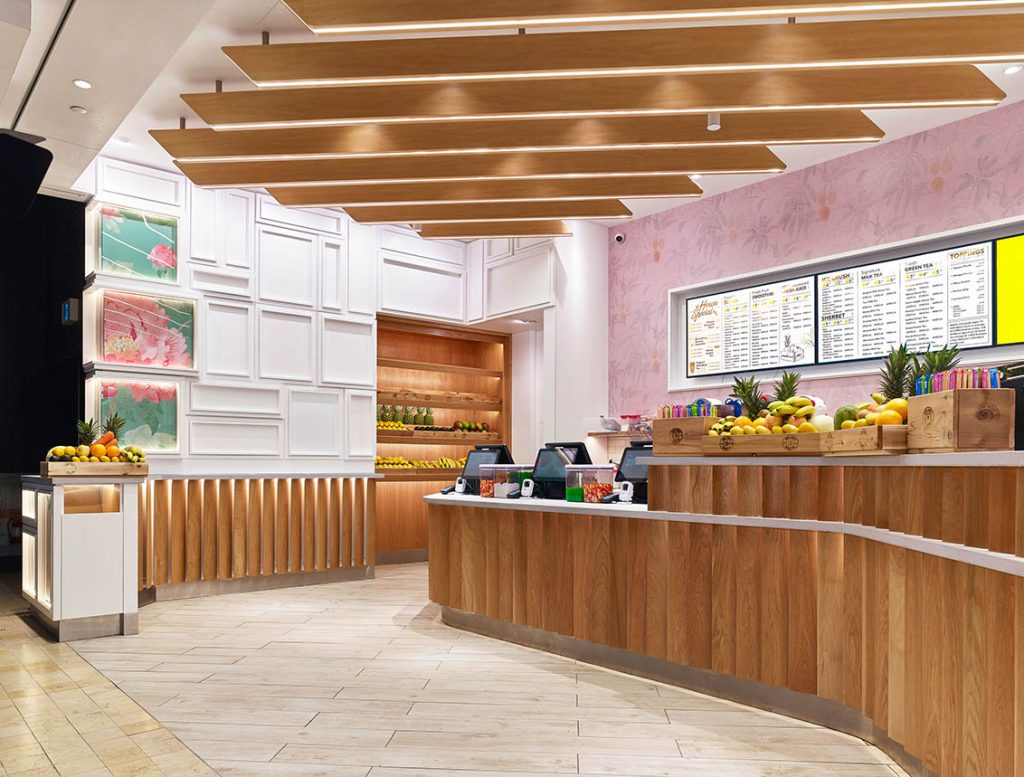 Close up of the interior showing the wooden planks placed on an angle on the white curved counter, and the wooden backlit planks on the ceiling to subtly direct customer flow.