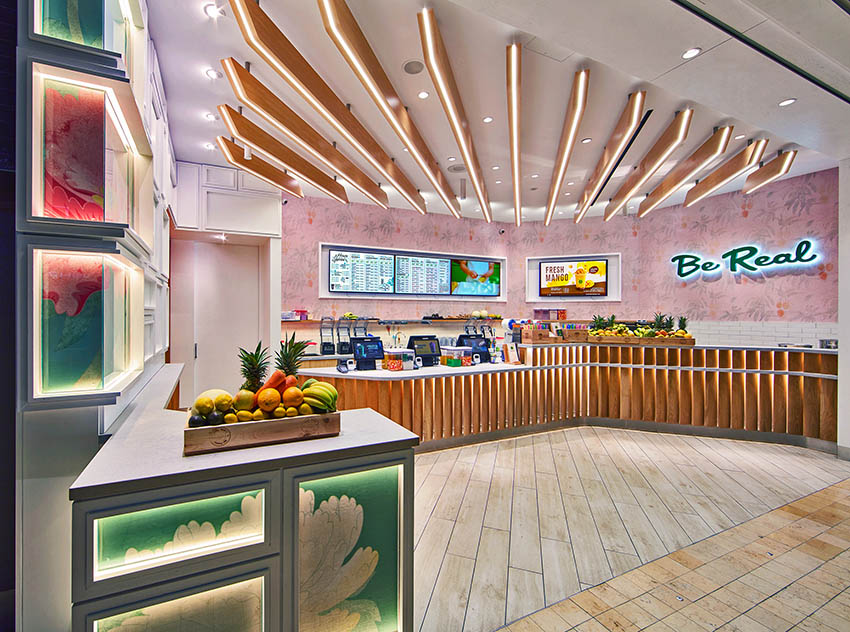 Close up of the interior showing the wooden planks placed on an angle on the white curved counter, and the wooden backlit planks on the ceiling to subtly direct customer flow.