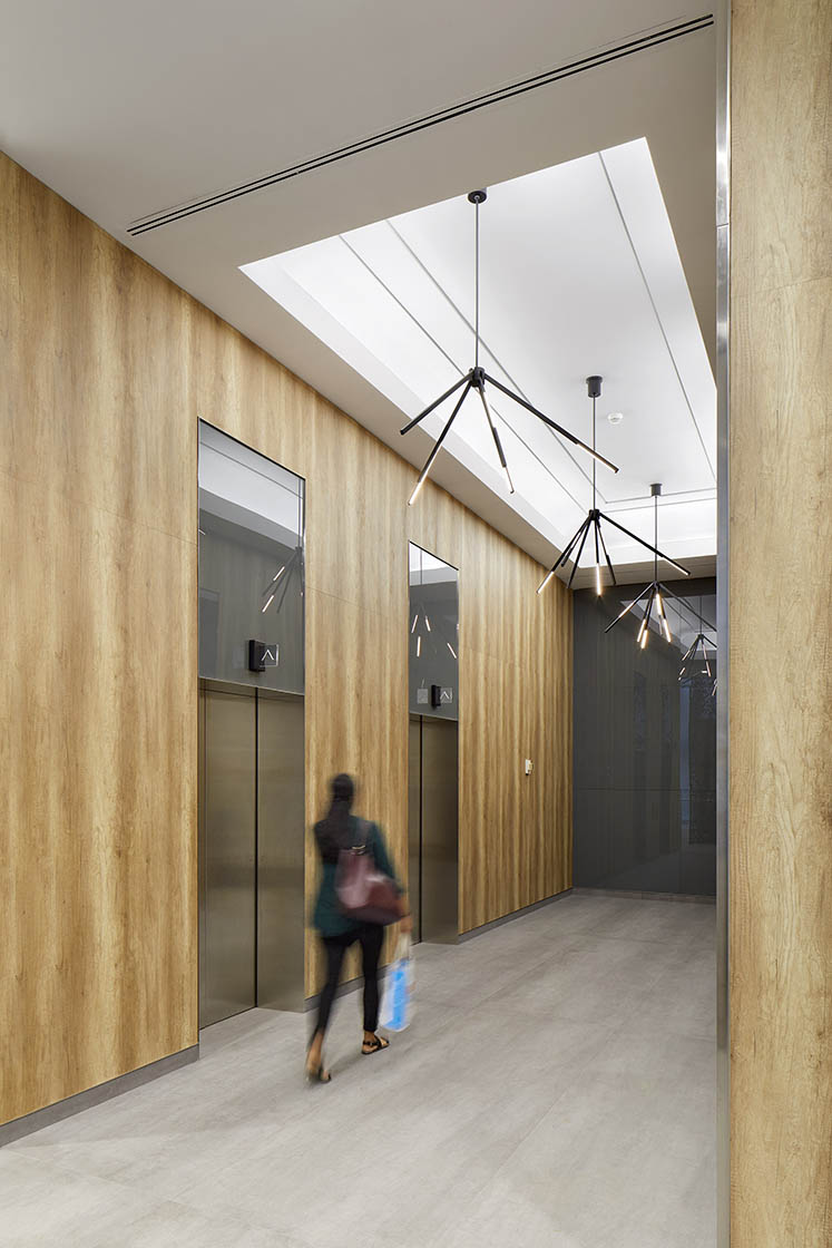 Elevator lobby with wood paneling and modern linear light fixtures in black finish