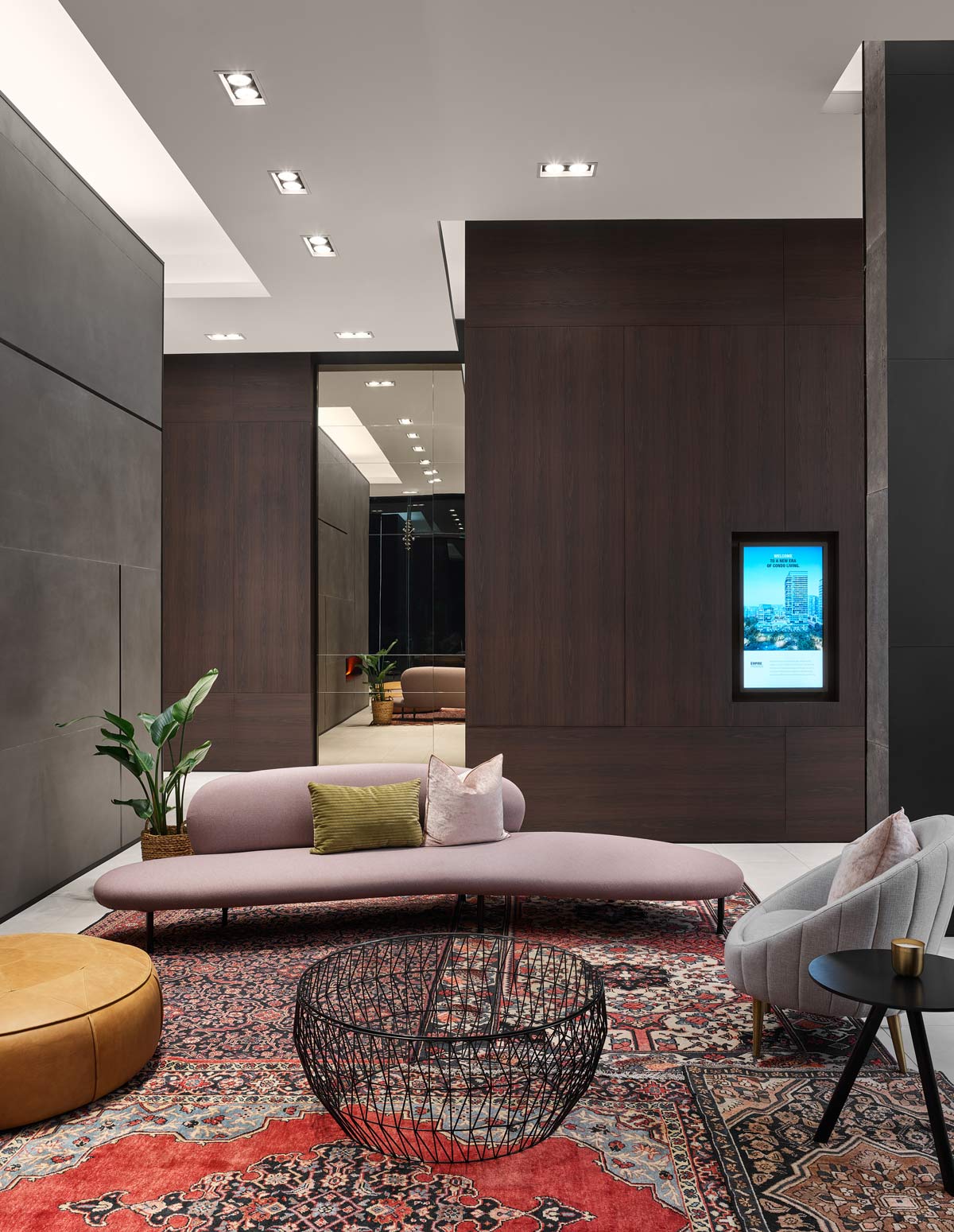 Another eclectic living room style lounge area in warm earthy tones and material, and stunning tall concrete wall on the side and a wood panel covered wall behind the setting
