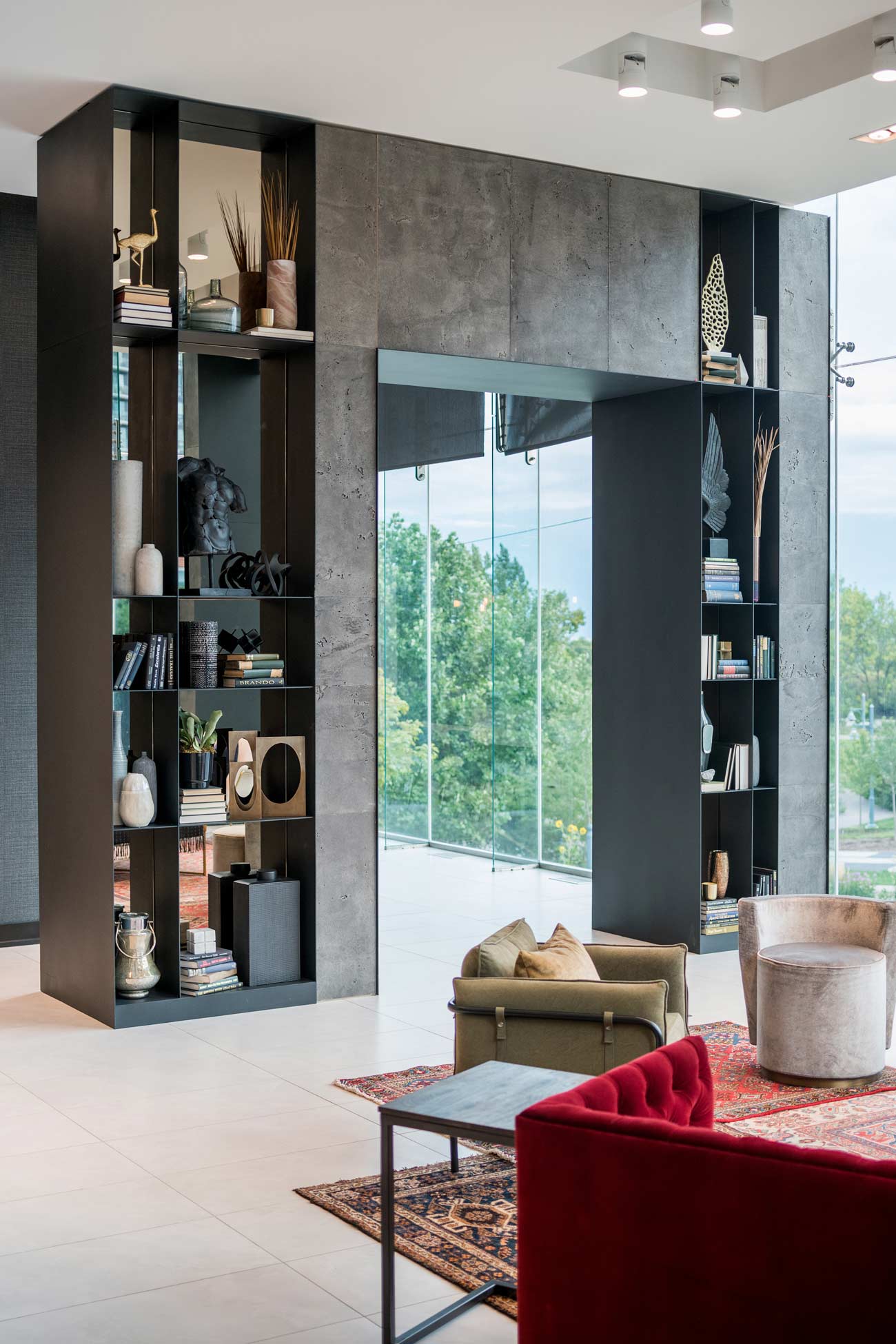 Another eclectic living room style lounge area in warm earthy tones and material, and stunning tall concrete wall on the side and a wood panel covered wall behind the setting