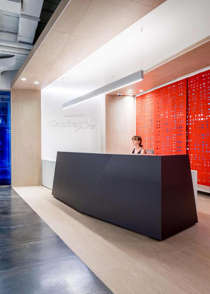 Modern clean lines of the black reception desk with an orange accent wall behind