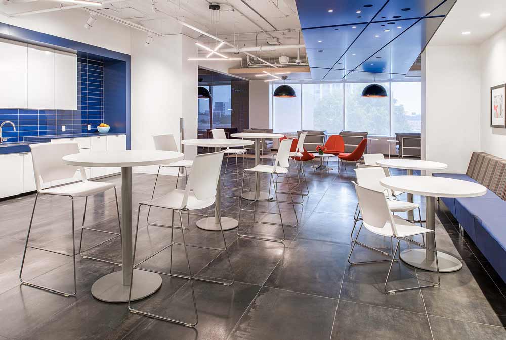 Cafeteria and lounge area primarily in white with pops of blue on the kitchen wall and the ceiling detail