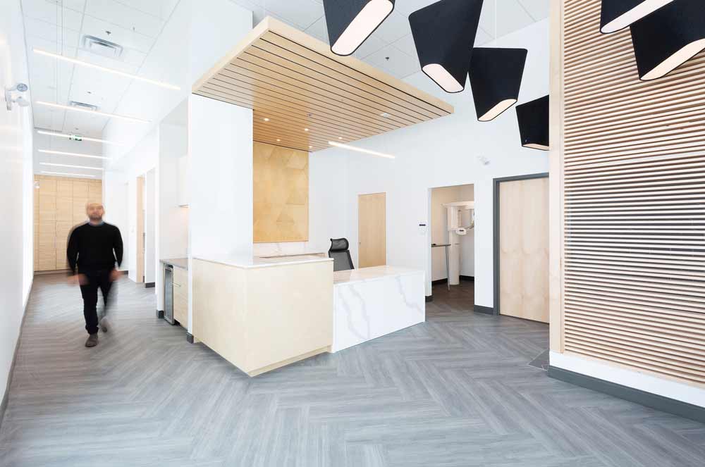 View of the reception desk from the waiting area. Desk is done in marble and wood combination of materials and a wooden slats detail above.