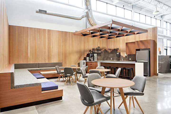 Open kitchen and lounge area with step seating along the wall and some tables and chairs also