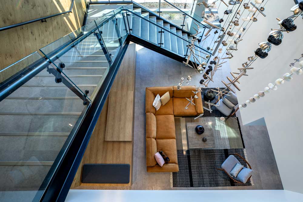 A view from the upper level looking down the chandelier piece at the lounge area below at the bottom of the staircase