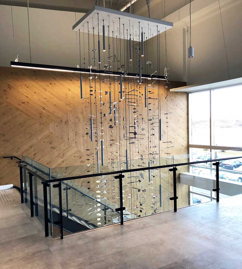A view of the Stryker chandelier piece from the second level looking toward the staircase with the wooden wall as a backdrop