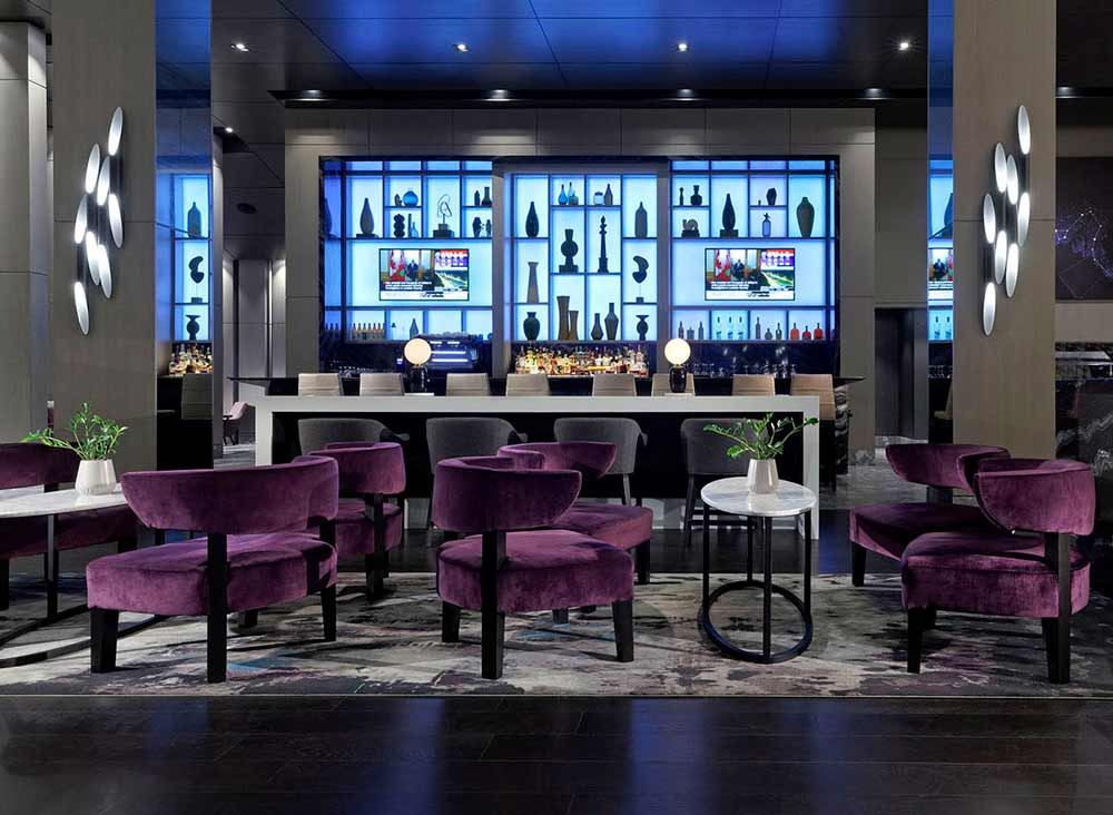 Bar area with a light blue shelving feature behind the bar and a relaxing lounge area with purple accent lounge chairs