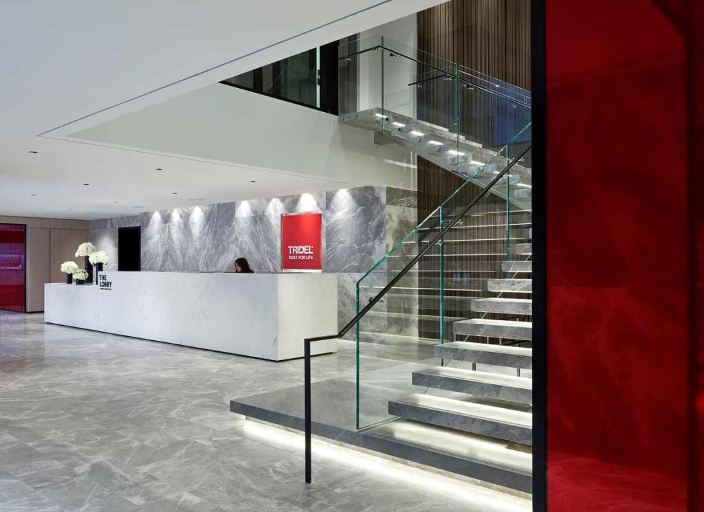 White marble reception desk on the ground floor with an impressive stair case right beside it leading upstairs