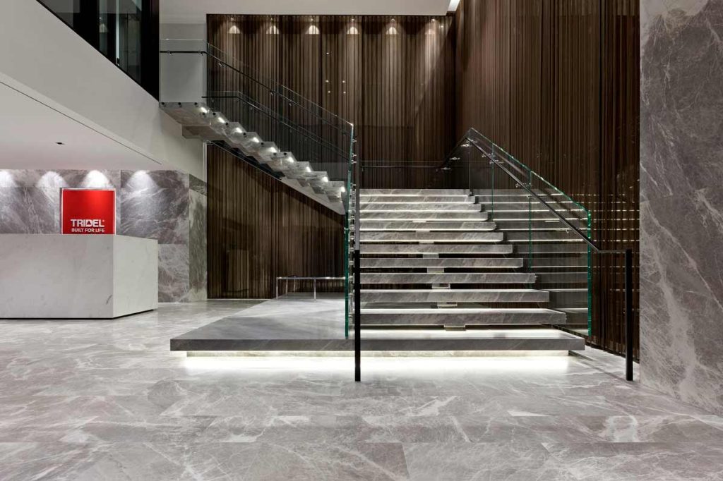 Impressive staircase is surrounded by bronze-tinted mirrors and floating on a spine supported by risers and self-illuminated LED treads