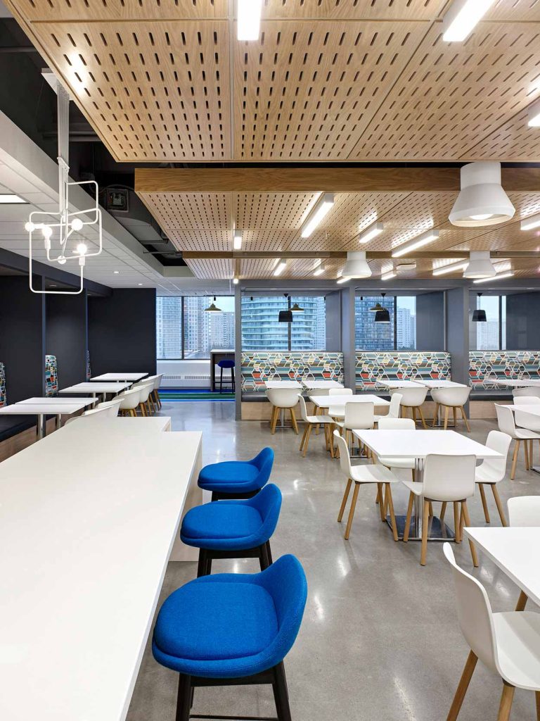 Bright and open cafeteria space with lots of tables and seating, with white and wood finishes and pops of blue