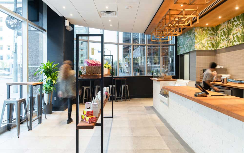 A view of the entire coffee shop along the length of the counter that leads towards the other end of the light filled space