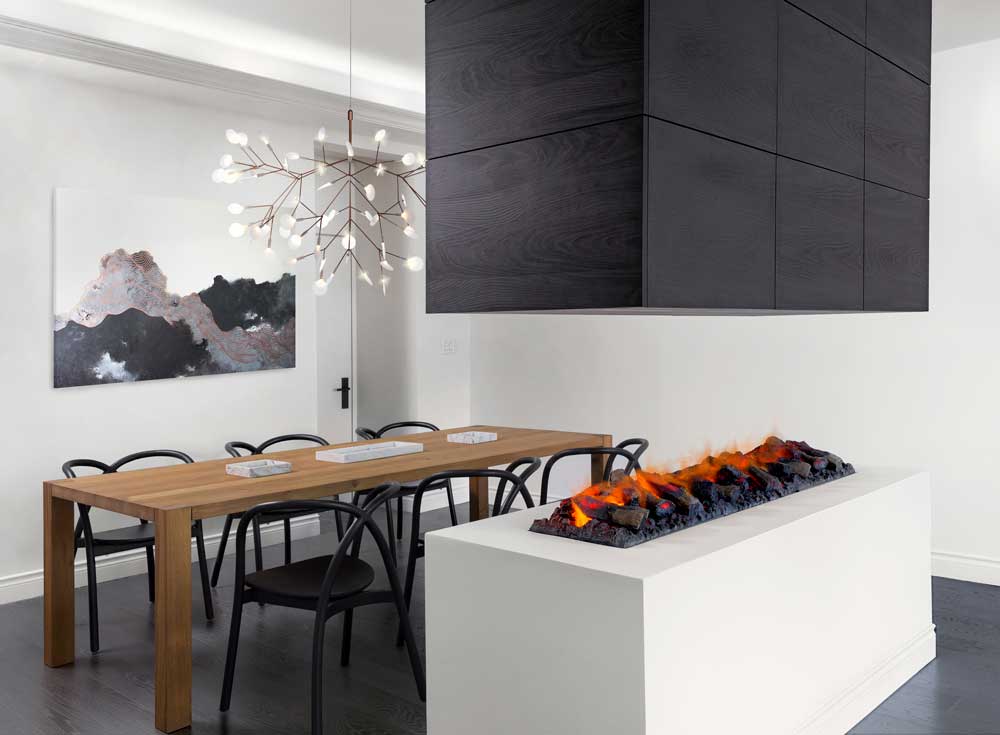 Formal dining room separated by a vapor fireplace is set in a crisp white pedestal and topped with a sleek black hood that doubles as storage