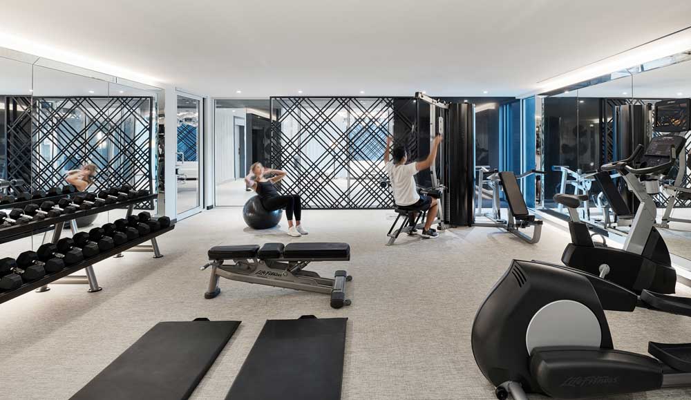 High end gym setting equipped with top of the line equipment and interesting geometric feature wall in the background