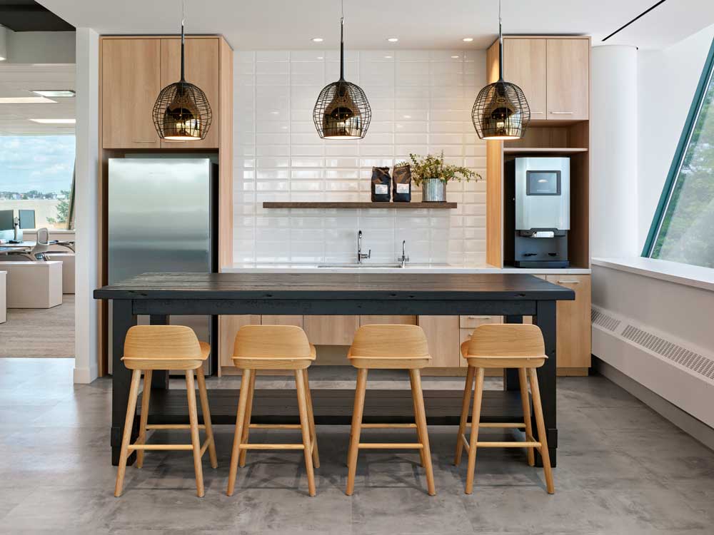 Wood finish kitchen with black accents and black coloured wooden island and seating around it
