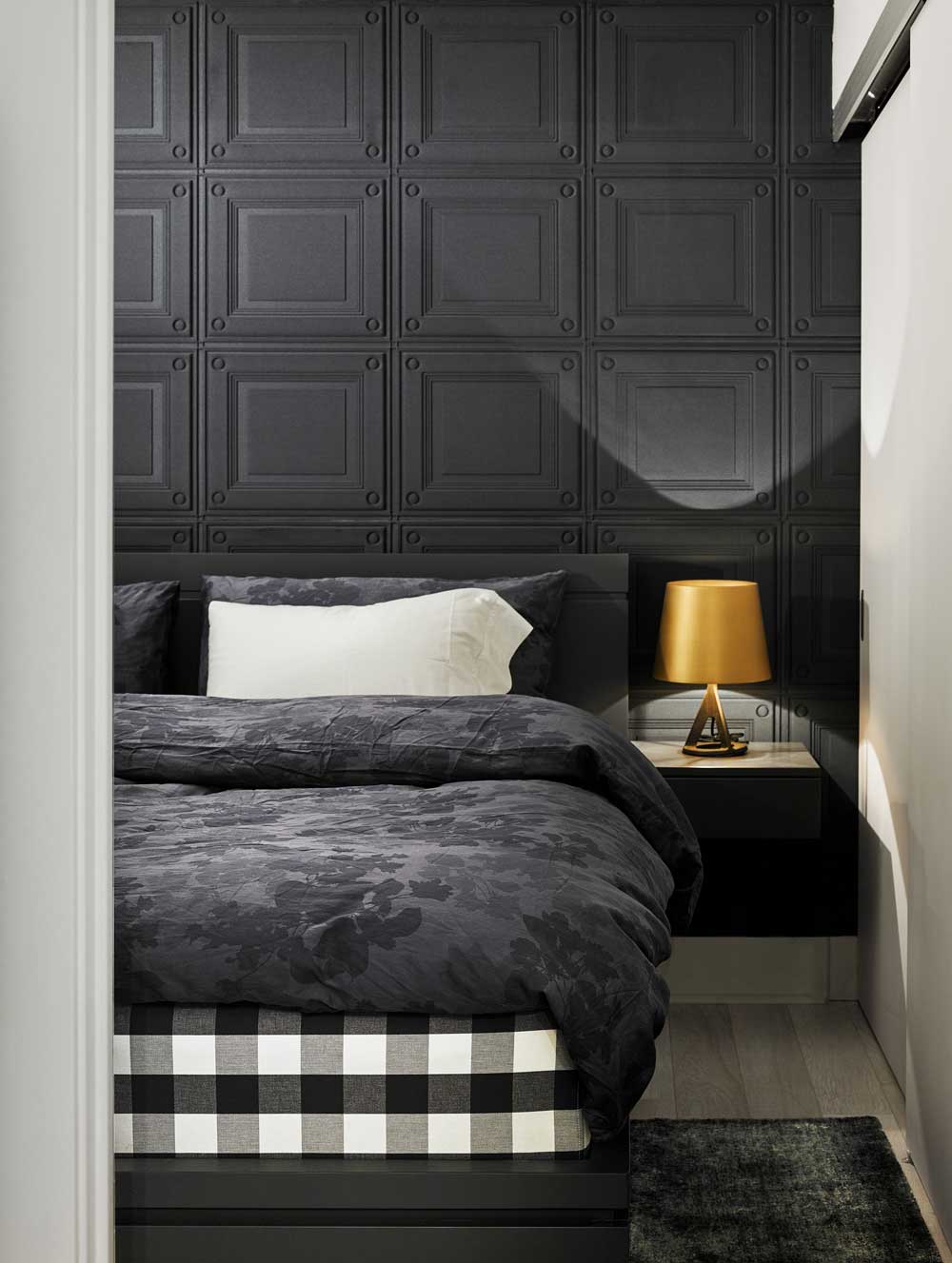 Bedroom wall with king bed and thick wall covering for sound proofing purposes on the wall behind it