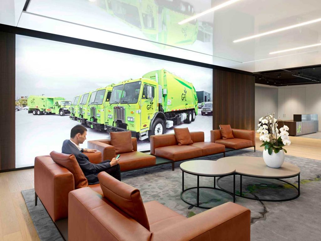 Waiting area off the reception desk area with Large graphic element on the wall in a form of oversized photograph of GFL green trucks