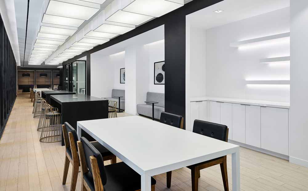Party room area with bar tables and stools in a long and narrow passage in a predominantly black and white colour scheme. This is a perfect co working space