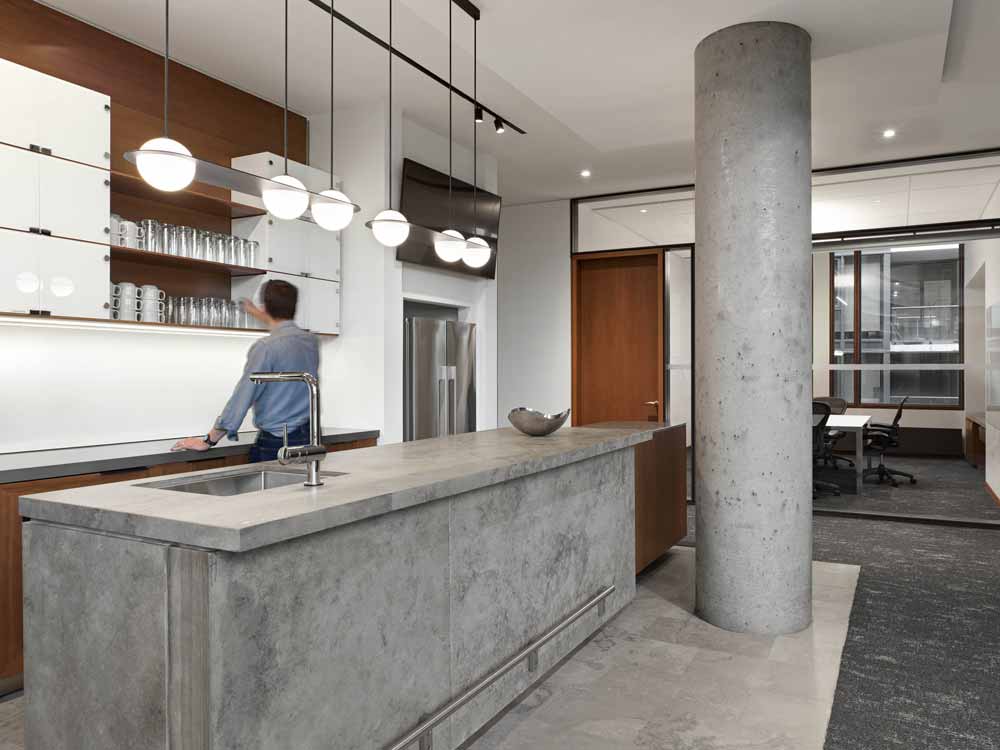 Modern kitchen incorporating wooden finishes with clean white cabinetry, modern lighting and a concrete island underneath