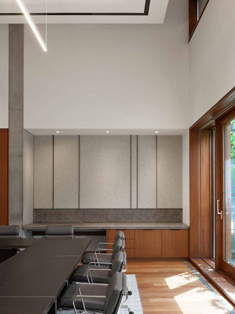 A simple and modern vignette in the boardroom, where wooden finishes dominate against white and concrete walls and modern grey boardroom furniture