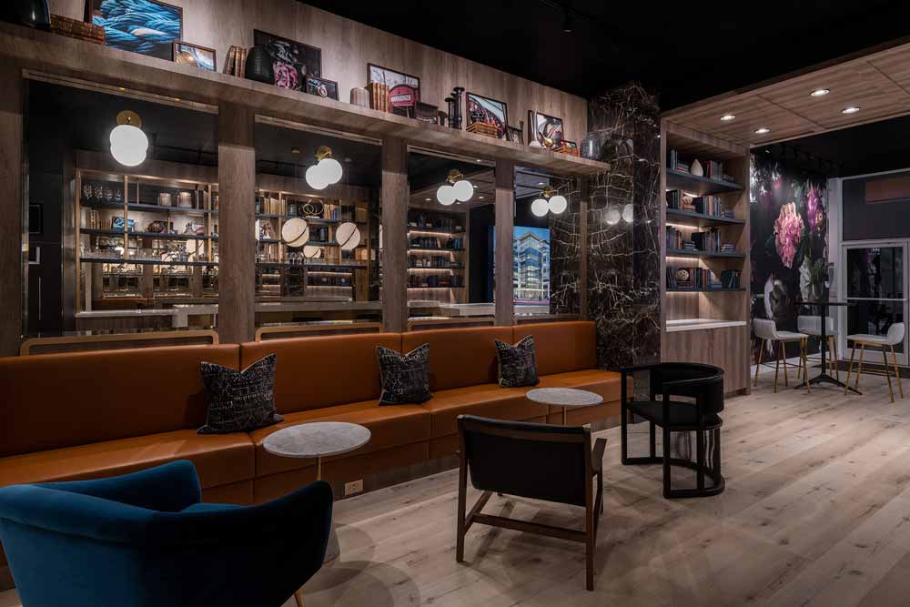 Lounge seating and above it is a wall of mirrors with reflection of the entire presentation centre making the space look larger