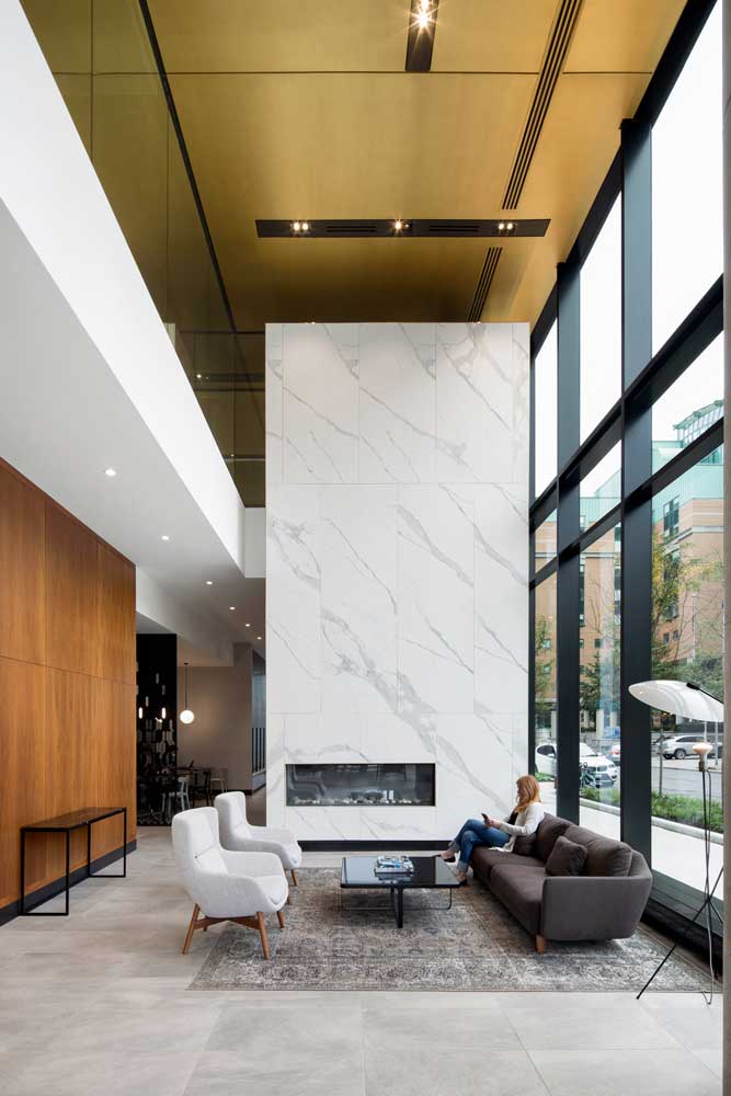 Double height feature fire place in the lobby lounge area with the cafe visible behind it