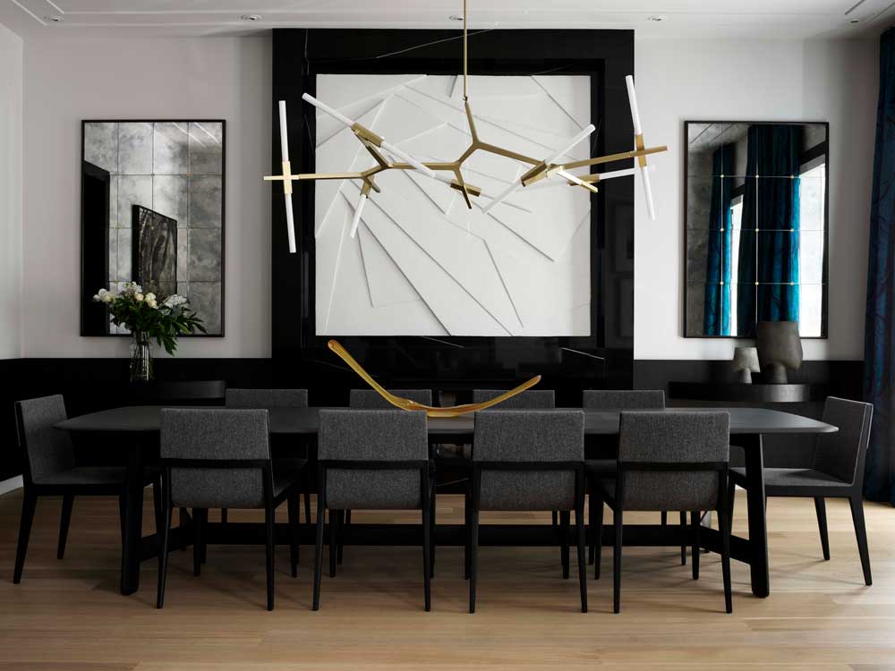 Dining area in gray and black with golden accents and a central wall feature with geometric design that anchors the space