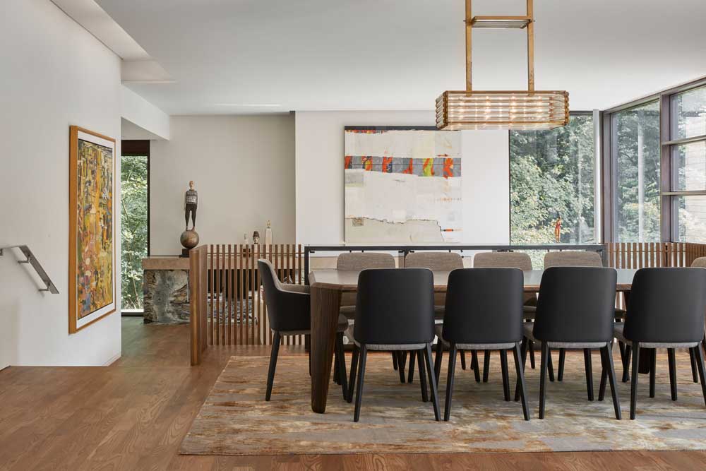 Dining room and sunken living room visible in the back. The entire space is surrounded by large windows that lets the outdoors in