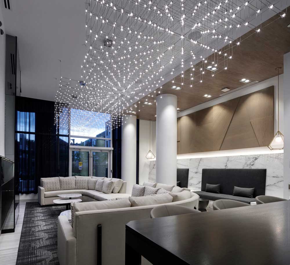 A big statement geometric light fixture hangs above the lounge area in the social lounge room with ample seating throughout