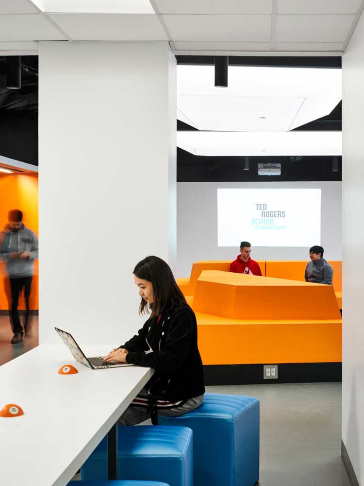 Small table for laptop use that stems off the main classroom, is decorated with moveable blue seating units