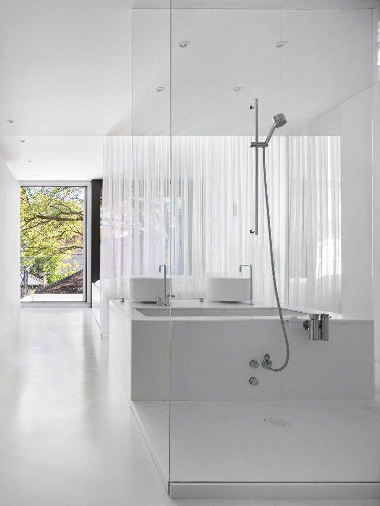 Main bedroom with enclosed bathroom in glass, with a white sheer curtain separating the two areas