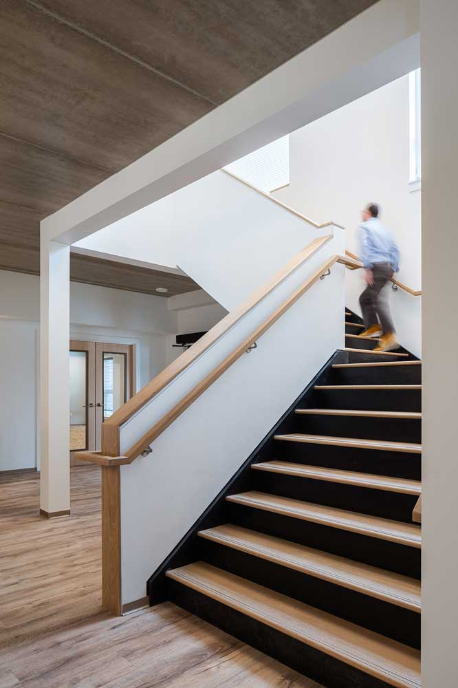 Staircase going up to the second floor with black risers and wood coloured steps create visual interest