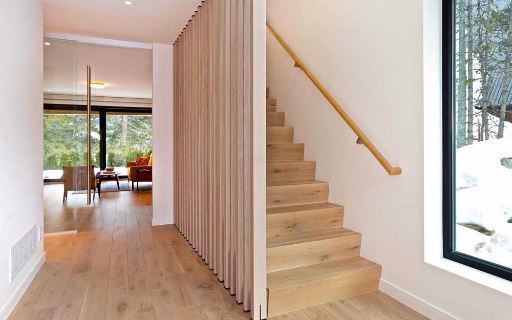 Lower level living room in the back and the prominent staricase that invites to the second floor