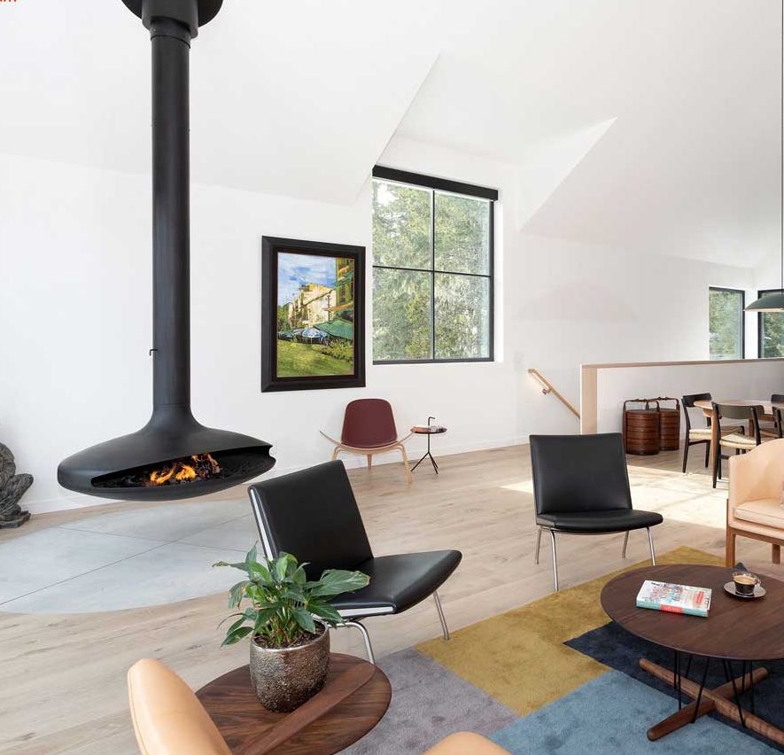 Second floor living area with comfy lounge area around a gyrofocus suspended wood burning fireplace