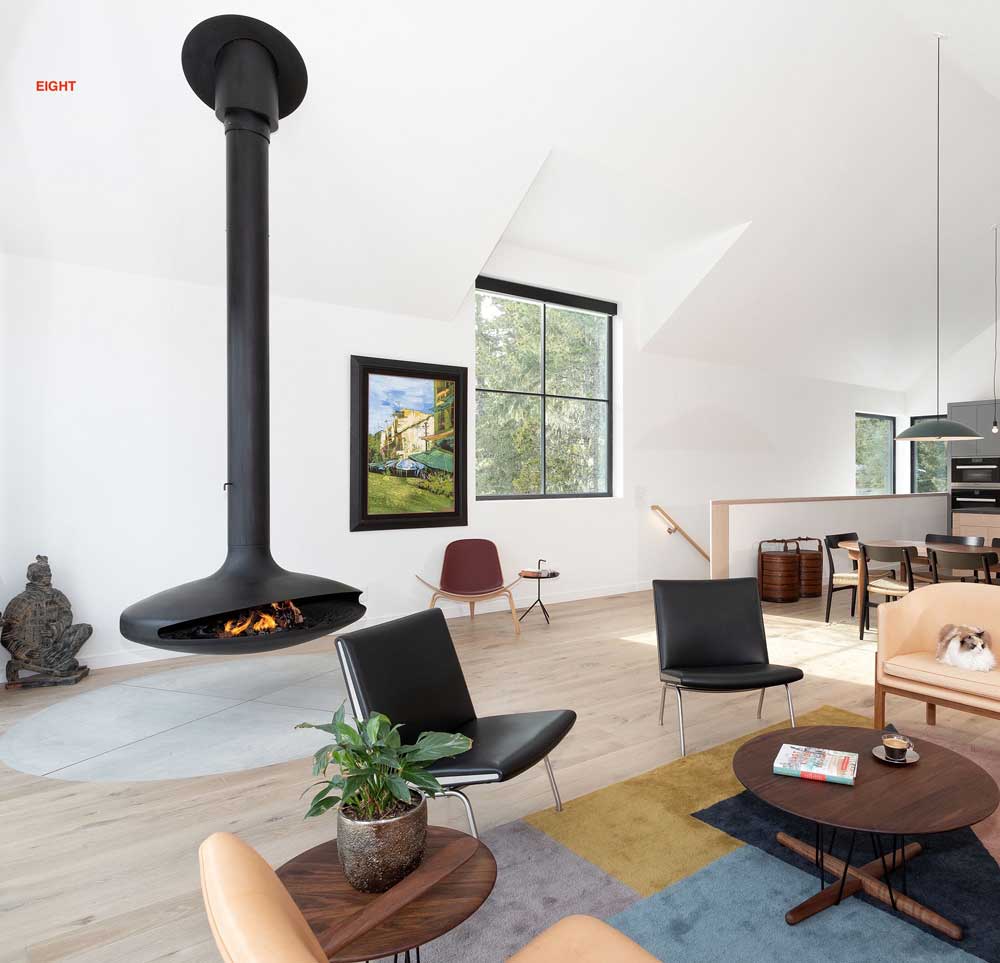 Second floor living area with comfy lounge area around a gyrofocus suspended wood burning fireplace