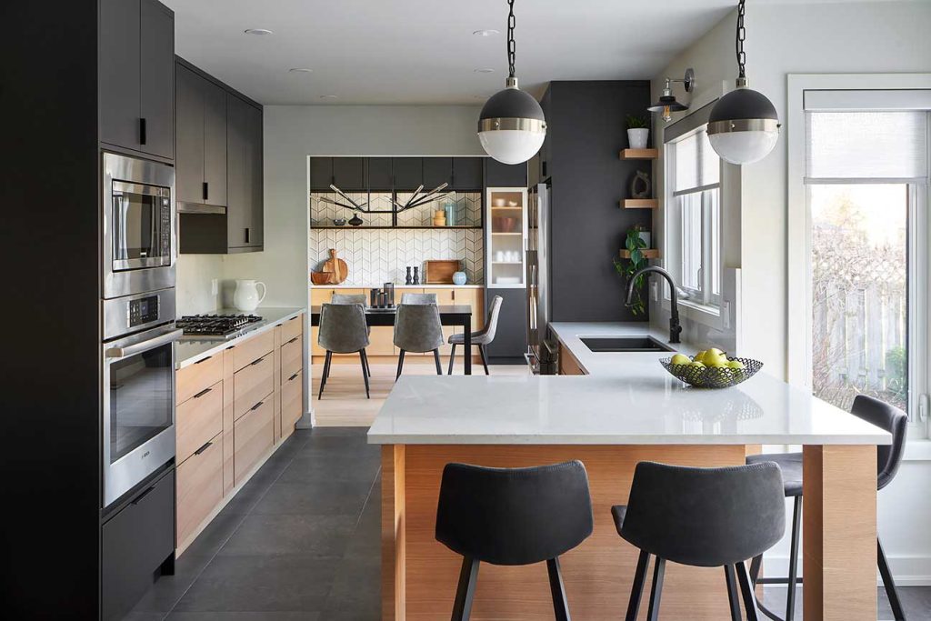 Modern kitchen with a large peninsula with bar stools and the dining area is visible in the back