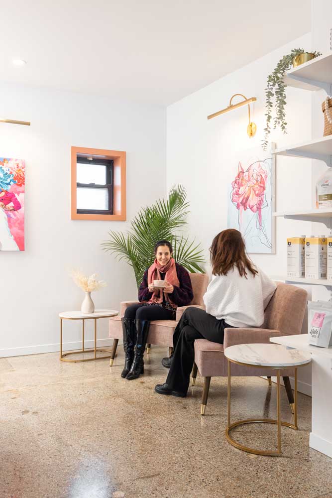 A little cozy lounge area at the very back of the store with furniture in blush pink and colourful abstract art on the walls