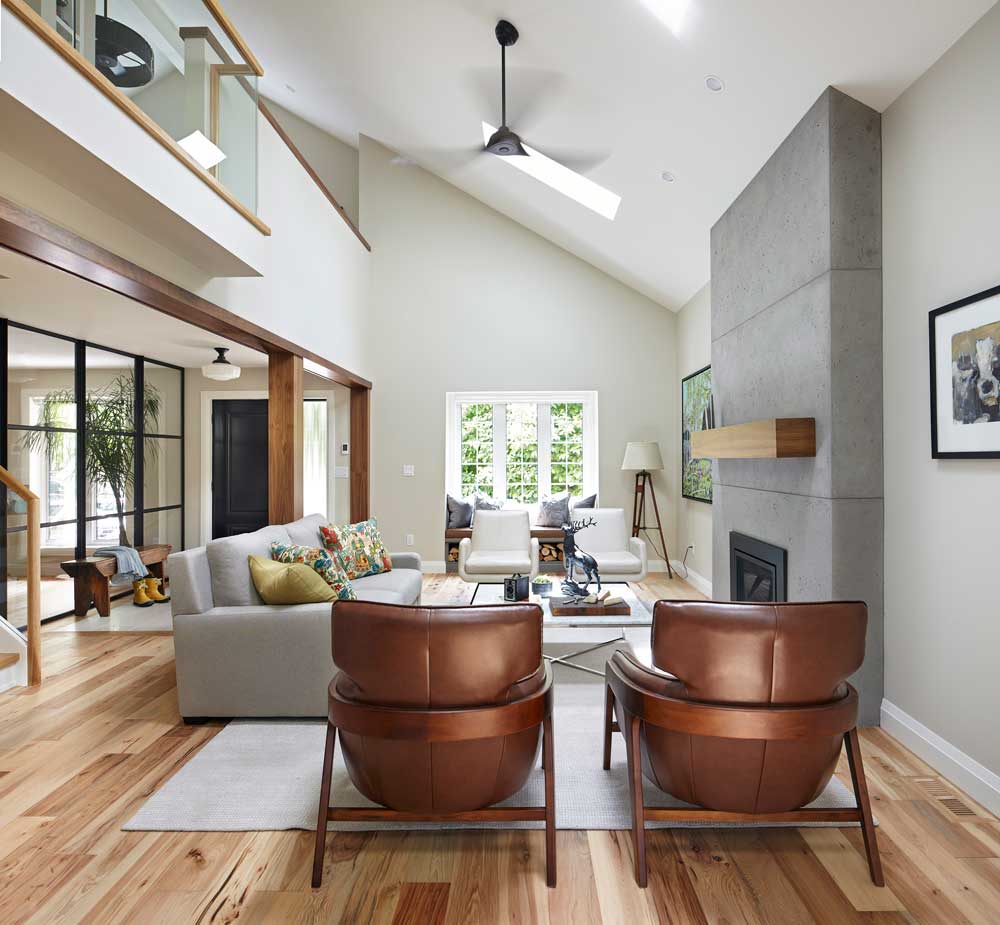 Light filled, open living room with a fire place as the focal point and furniture around it, with vaulted ceilings above
