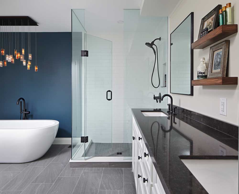Modern ensuite with a shower and free standing tub and a statement light fixture above it