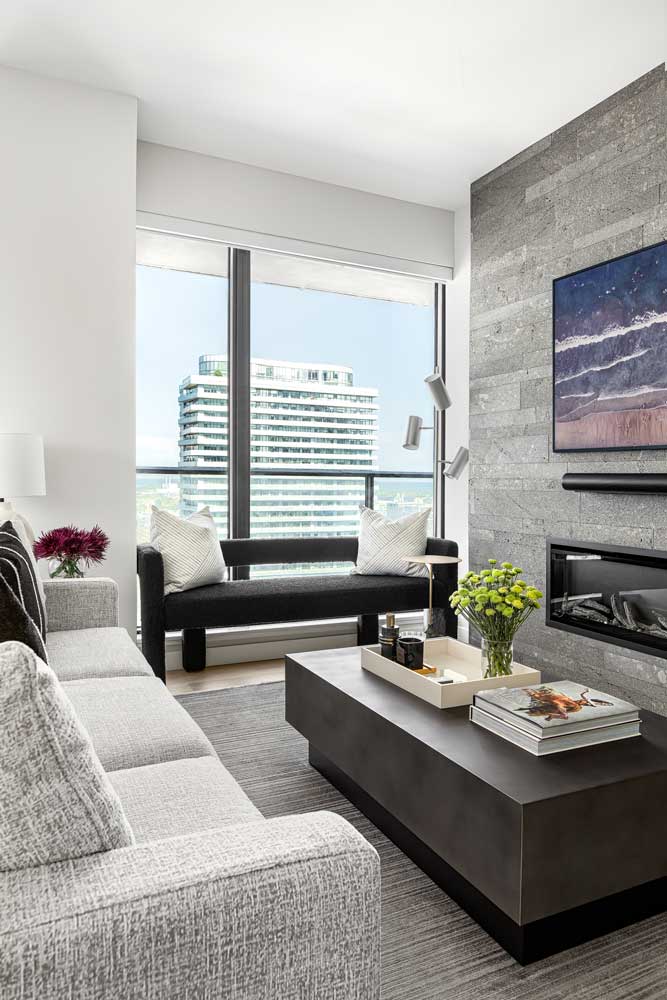 Feature wall in the living room, with modern monochromatic furniture placed around the fireplace looking over the city