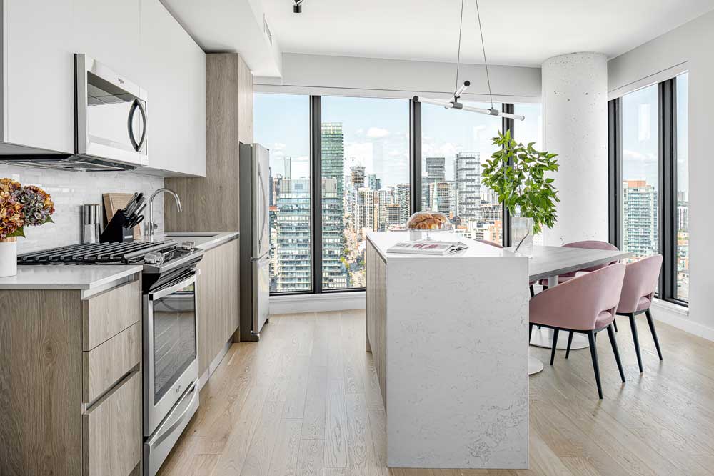 Beautiful two tone Kitchen and dining area showing the angled table with the stunning views of Toronto in the background