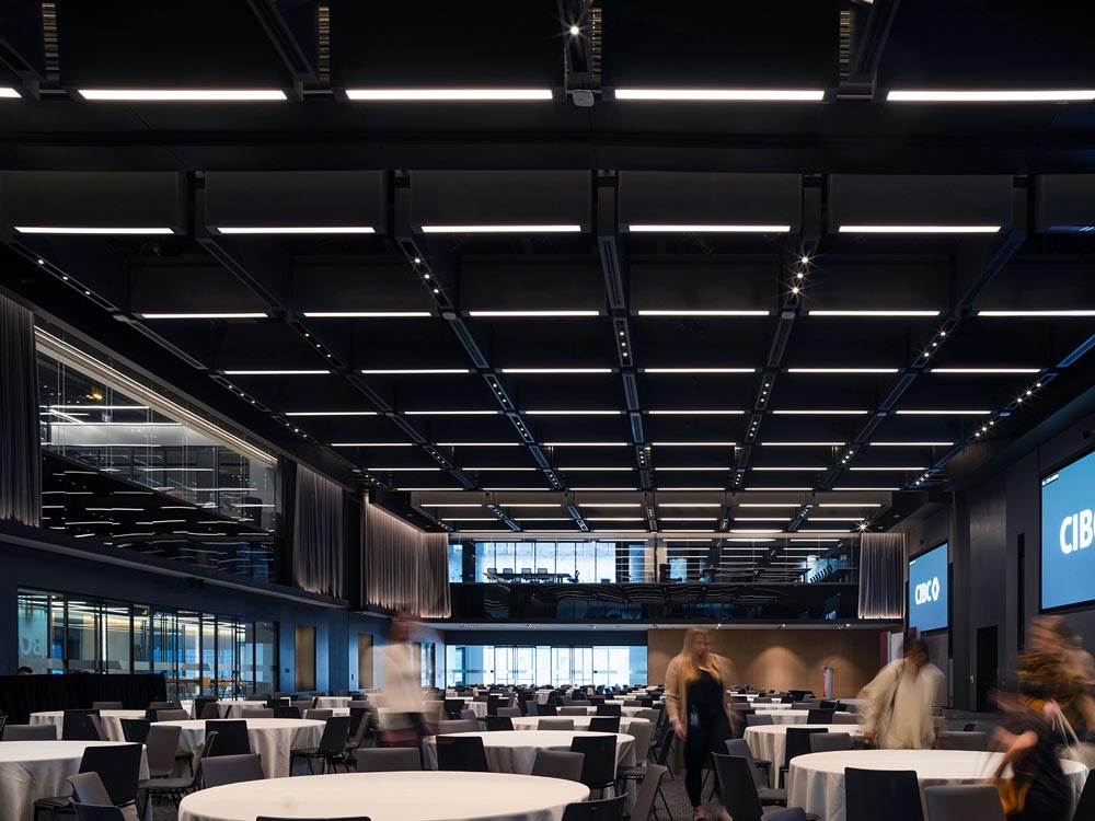 Large Conference room with multiple round tables, two storey ceiling with linear lighting running across in a square pattern