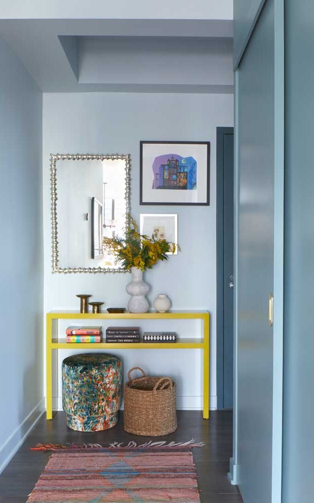 Foyer with bright lemon yellow console table against the light blue walls with a small gallery wall