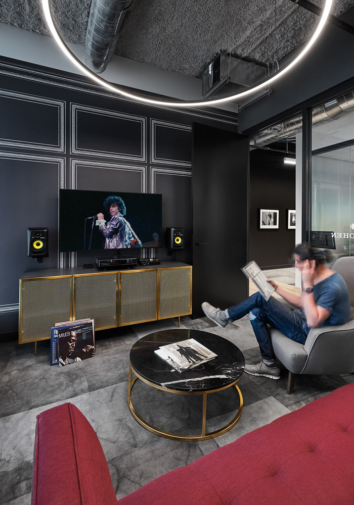 A comfortable space meant for collaboration or private, quiet work with mid century modern touches and colourful accents like the red sofa