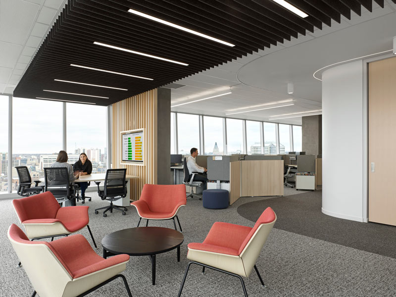 Relaxed seating area with the work station area visible in the back. The entire space is surrounded by floor to ceiling windows