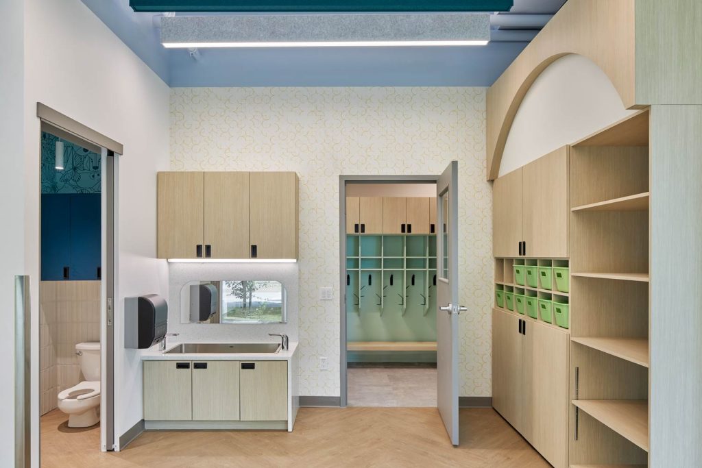 Washroom equipped with tiny toilets and sinks, and plenty of storage cabinetry