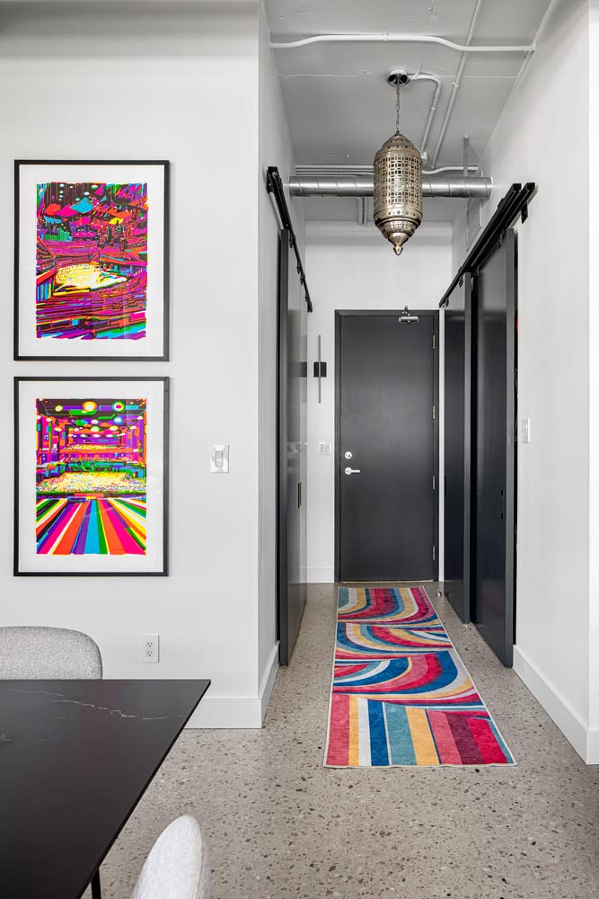 A look toward the front door and entrance, featuring bright coloured runner that goes perfectly with bright pink artwork on the wall